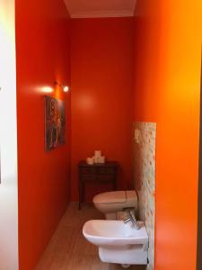 a bathroom with two toilets and an orange wall at Casa Beija-Flor in Mogofores +12 photos