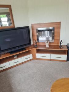 una sala de estar con TV en un centro de entretenimiento de madera en Beautiful 3 bedroom holiday home Amazing views, en Gisburn