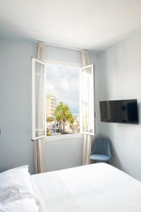 una camera da letto con finestra, letto e sedia blu di Albium - Hotel Sul Mare ad Albenga