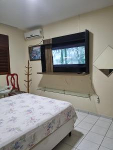 1 dormitorio con 1 cama y TV de pantalla plana en Sua casa fora de casa en João Pessoa