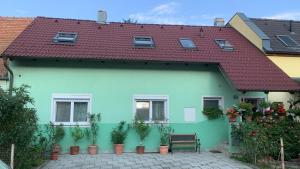 una casa verde con techo rojo y macetas en 100qm comfort, family-friendly and top located en Guntramsdorf