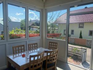 a screened porch with a table and chairs and windows at Ferienwohnung Regau 