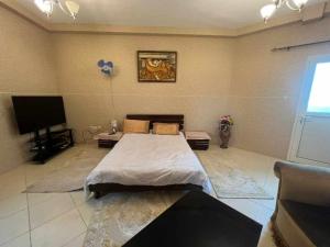 Schlafzimmer mit einem Bett und einem Flachbild-TV in der Unterkunft شقة مفروشة دبي in Ajman 
