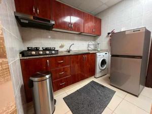 eine Küche mit Holzschränken und einem Kühlschrank aus Edelstahl in der Unterkunft شقة مفروشة دبي in Ajman 