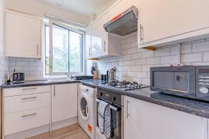 a white kitchen with a stove and a microwave at Bright 1 Bed Flat near London Bridge in London