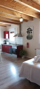 Habitación con cocina con armarios rojos y mesa. en La Casona del Asno en Alcalá de Henares