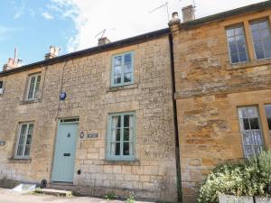 an old stone building with a blue door at Red Fawn Cottage in Blockley