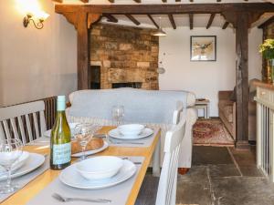 ein Esszimmer mit einem Tisch und einer Flasche Wein in der Unterkunft Red Fawn Cottage in Blockley + 22 Fotos