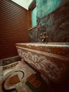 a bathroom with a stone tub and a mirror at Villa Parku Rinia in Korçë