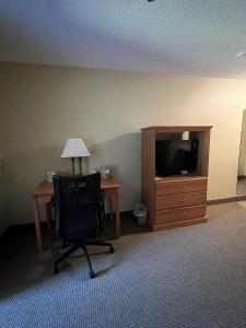 Cette chambre comprend un bureau, une télévision et une chaise. dans l'établissement Country Inn Walker, à Walker