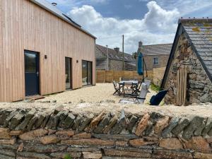 un patio con una mesa y una sombrilla junto a un edificio en La cabane du banc José, en Le Rozel
