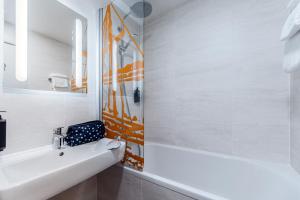 an orange and white bathroom with a sink and a mirror at ibis Styles Ancenis Centre in Ancenis