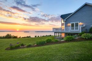 a house on a hill with the sunset in the background at Waterfront Lake Champlain Home with Hot Tub and Sauna! in Melville Landing