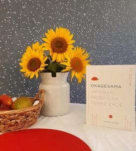 a vase with sunflowers in it next to a basket of fruit at Apartament City Center JAPAN - no smoking, free bottled water, coffea and tea in Koszalin