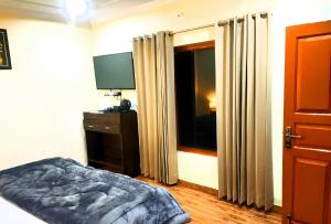 a bedroom with a bed and a television and a window at Hill Veda Homestay in Kanatal