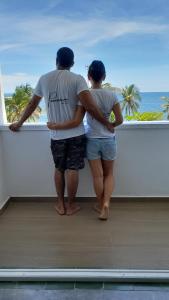 a man and woman looking out of a window at the ocean at Panamerican Hostel in Santa Marta +82 photos