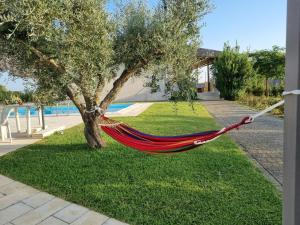 a red hammock hanging from a tree in a yard at Accogliente villa con piscina in Caltagirone