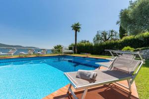 a swimming pool with a chaise lounge and a chair next to it at Villa Aurora- Villa esclusiva con piscina e splendida vista lago in Gargnano