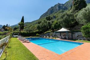 a swimming pool with chairs and a mountain in the background at Villa Aurora- Villa esclusiva con piscina e splendida vista lago in Gargnano