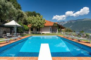 a swimming pool with chairs and a house at Villa Aurora- Villa esclusiva con piscina e splendida vista lago in Gargnano