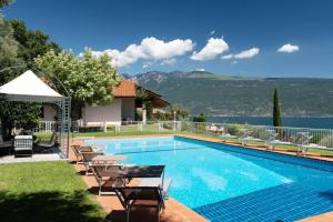 a swimming pool with chairs and a view of the water at Villa Aurora- Villa esclusiva con piscina e splendida vista lago in Gargnano
