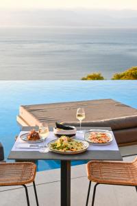 a table with two plates of food and wine glasses at ​Le Grand Bleu Resort in Derveni