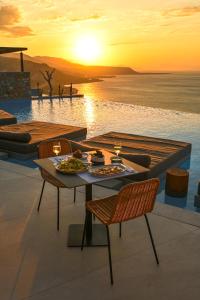 einen Tisch und Stühle auf einer Terrasse mit Blick auf den Sonnenuntergang in der Unterkunft ​Le Grand Bleu Resort in Derveni