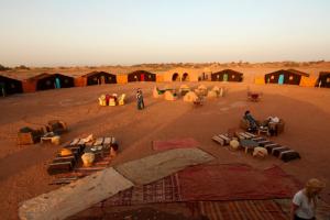eine Gruppe von Menschen in einer Wüste mit Zelten in der Unterkunft Bivouac M'hamid Le Pacha in M’hamid El Ghizlane