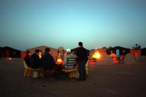 a group of people sitting in chairs in a desert at Bivouac M'hamid Le Pacha in Mhamid