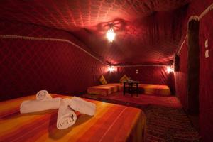 a room with two beds in a red room at Bivouac M'hamid Le Pacha in Mhamid