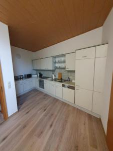 a large kitchen with white cabinets and a wooden floor at Suite Toni in Bernburg