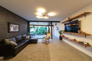 sala de estar con sofá de cuero y TV de pantalla plana en Hostal Casa Mosaiko Primer Parque-Laureles, en Medellín