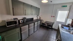 uma cozinha com um balcão com um micro-ondas e um lavatório em Luxury double room with kitchen facilities em Nottingham