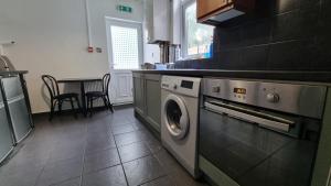uma cozinha com uma máquina de lavar roupa e uma mesa em Luxury double room with kitchen facilities em Nottingham