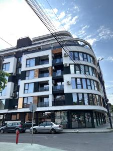 un gran edificio con coches estacionados frente a él en Ultra Lux Apartment Free Underground Parking en Pazardzhik