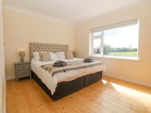a bedroom with a large bed and a window at Glanffraw in Aberffraw