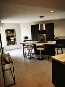una cocina con armarios negros, mesa y taburetes en Villa spacieuse et stylée à 50m de la plage en Carnon-Plage