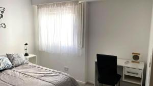 1 dormitorio con cama, escritorio y ventana en Rosales.RM - Depto completo 2 ambientes con patio. en Ramos Mejía