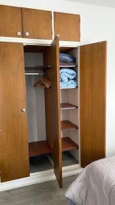 a closet with wooden doors and shelves in a bedroom at Rosales.RM - Depto completo 2 ambientes con patio. in Ramos Mejía