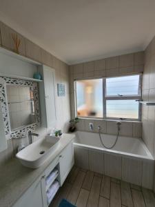 a bathroom with a tub and a sink and a window at Seaside Tresure. in Mossel Bay