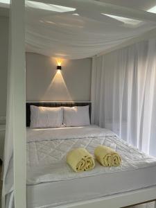 Una cama blanca con dos almohadas amarillas. en Royal Nile Villas - Nile View Apartment 1, en Luxor