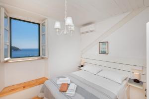 a white bedroom with a bed and a large window at Tik tak Dubrovnik 2 in Dubrovnik