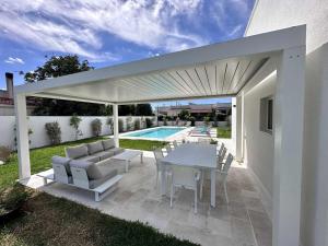 un patio con mesa, sillas y piscina en Casa del Sol Luxury Estate Puglia, en Leporano Marina