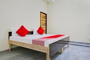 Bett in einem Zimmer mit roten Kissen darauf in der Unterkunft OYO Flagship Skyway Residency in Indraprast