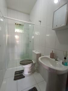 a white bathroom with a toilet and a sink at Excelente casa na praia em Matinhos PR. 600 metros da praia. in Matinhos