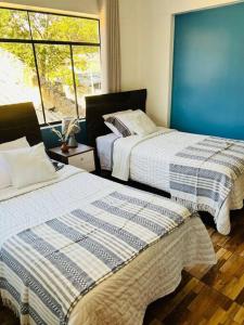 two beds in a room with a window at Qouyllur House in Marcará