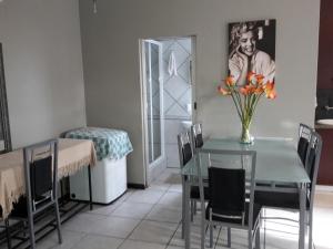 a dining room with a table with a vase of flowers on it at Abby's Guesthouse in Port Elizabeth