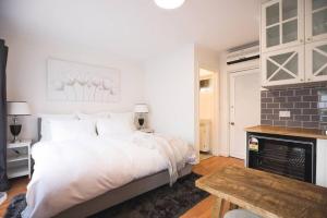 a bedroom with a large white bed and a table at Studio Escape North Adelaide in Adelaide
