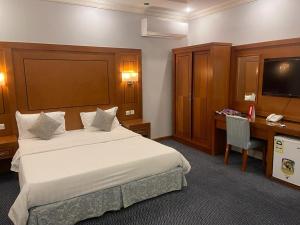 a hotel room with a bed and a desk and a television at رغد الشاطئ للاجنحة الفندقية in Jeddah