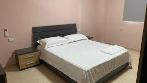 a bedroom with a bed with white sheets and a night stand at Anna´s apartament in Lushnjë